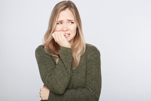A woman biting her nails and looking distressed